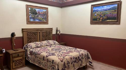 a bedroom with a bed and two paintings on the wall at Hotel Hacienda San José in San Francisco del Rincón