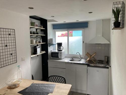 Una pequeña cocina con fregadero y ventana. en Studio Cosy, en Saint-Quay-Portrieux