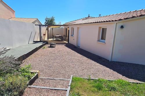 une arrière-cour d'une maison blanche avec une terrasse dans l'établissement L'Ouvéa joli gîte à 10 min du parc le Puy du Fou, à Sevremont