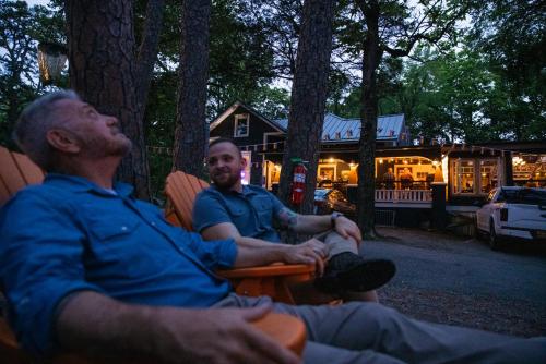 two men sitting in chairs in front of a cabin at The Wanderoo Lodge in Eureka Springs