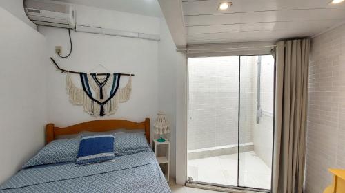 1 dormitorio con 1 cama y puerta corredera de cristal en Apto 2 Quartos com Ar a 200m da Praia, en Florianópolis