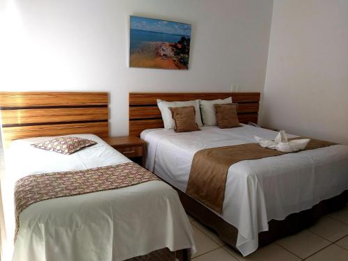 Cette chambre d'hôtel comprend 2 lits avec des draps blancs. dans l'établissement Hotel Estrela Mares, à Três Marias