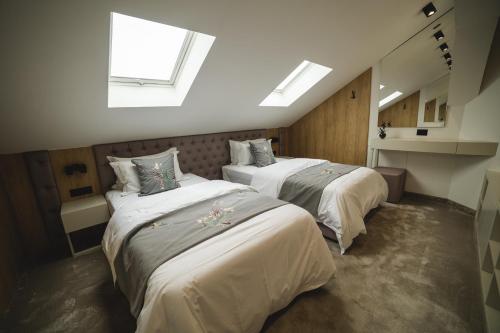 two beds in a room with two windows at Apartmanski smestaj King Bo in Niš