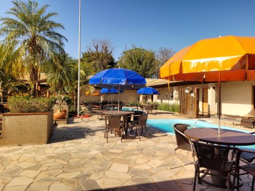a patio with tables and umbrellas next to a pool at Hotel Pousada Parque das Águas in Olímpia