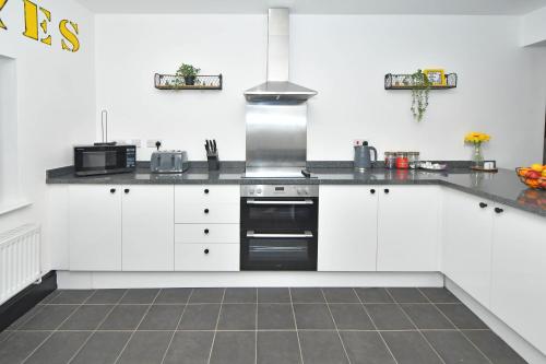 a kitchen with white cabinets and a stove top oven at Potter's Rest by YourStays in Stoke on Trent