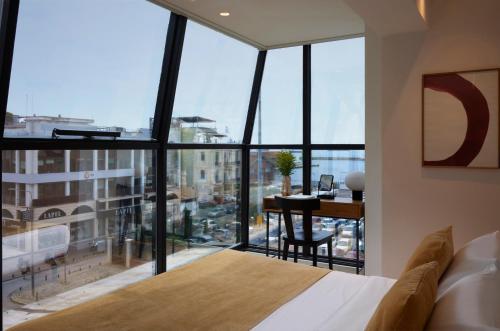 a bedroom with a bed and a large window with a desk at Noa Hotel in Thessaloniki
