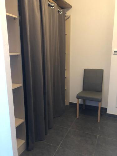 Zimmer mit einem Stuhl und einem Vorhang in der Unterkunft Large studio with private parking Vallauris in Vallauris