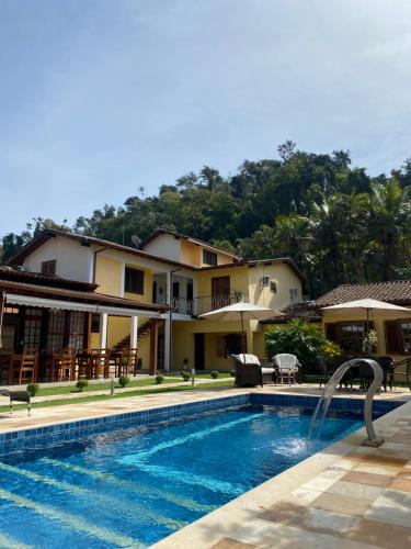 a villa with a swimming pool in front of a house at Pousada Antígona in Paraty