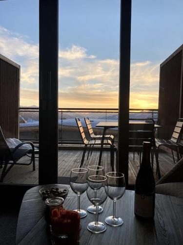 a table with wine glasses and a bottle on a balcony at Luxurious duplex for 4-7p with large terrace and pool in ski-in ski-out 5 star residence at Les Arcs in Bourg-Saint-Maurice