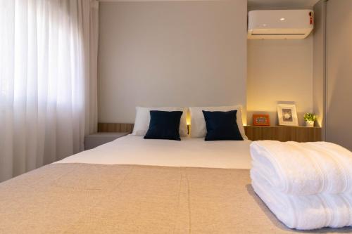 1 dormitorio con 1 cama blanca grande con almohadas azules en Avenue Studio - GRU, en Guarulhos