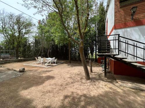 a patio with chairs and a tree next to a building at Finca Los Molinos in La Alameda de Cervera
