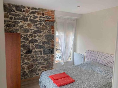 sypialnia z łóżkiem i kamienną ścianą w obiekcie Precioso Piso muy cerca de la playa de salinas, Eysines 34 1izq w mieście Piedras Blancas