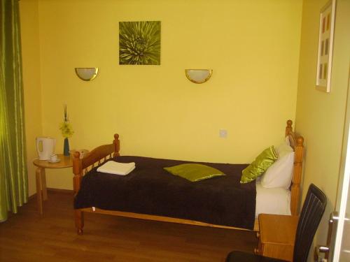 a bedroom with a bed with a black blanket and a table at Stansted Airport Lodge in Takeley