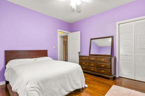 1 dormitorio con paredes moradas, 1 cama y espejo en The Pink Room near Yale Hospital/Bridegport en Bridgeport