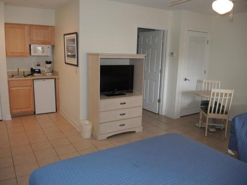 a living room with a television and a kitchen at Brunswick Plantation Resort and Golf Villas 2302L in the Heart of NC Seafood Country studio in Calabash