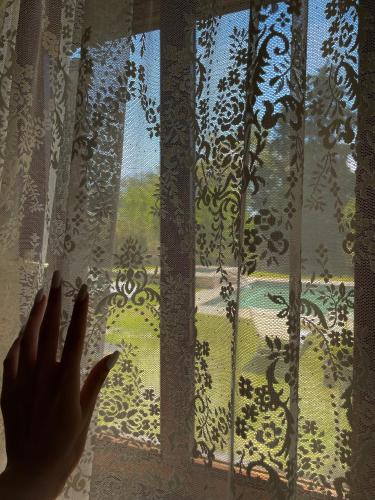 a persons hand is reaching for a window curtain at Siviri Traditional Stone House in Siviri