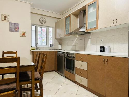 a kitchen with a table and a stove and cabinets at Apartment in Paiania near the airport in Paianía