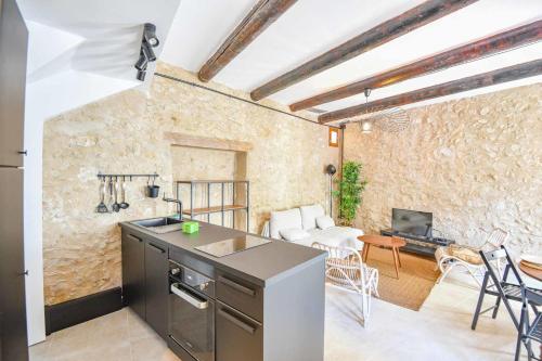 Il comprend une cuisine et un salon avec un mur en pierre. dans l'établissement Maison de charme 2 ch à Vauban proche Vieux Port, à Marseille