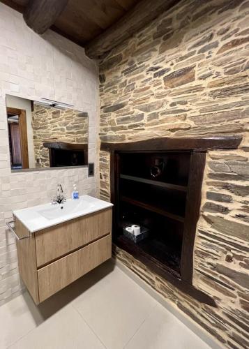 baño con lavabo y pared de piedra en Casa A Poza en Samos