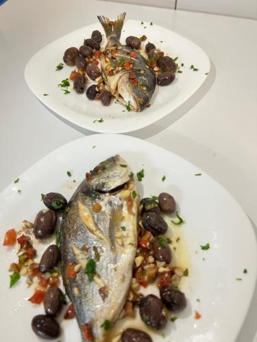 two plates of food with fish and black beans at Hotel Ergi in Durrës
