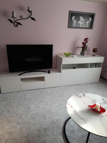 una sala de estar con TV y un centro de entretenimiento blanco en Ferienwohnung Zawalla, en Kamminke