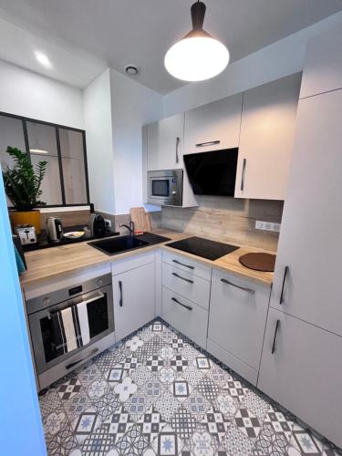 une cuisine avec des armoires blanches et un sol carrelé dans l'établissement La Bulle Dorée, à Épernay