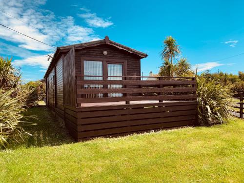 a small cabin with a fence in the grass at Lagavulin 3 in Portpatrick