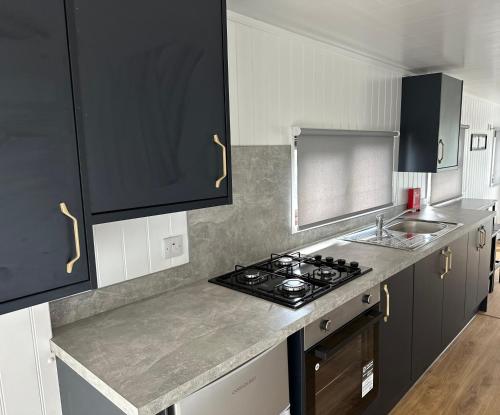 a kitchen with black cabinets and a stove top oven at Lagavulin 3 in Portpatrick