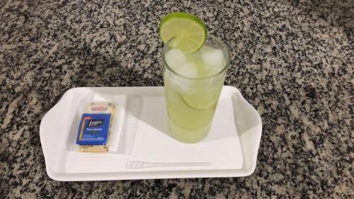 uma bebida com limão num prato com um lanche em 24 Horas Motel Jaguar Contagem em Contagem