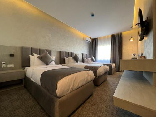 a hotel room with two beds and a couch at Kaya Hotel Amman in Amman