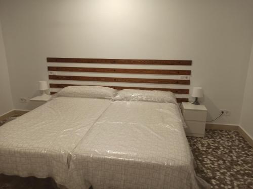 a bedroom with a white bed with a wooden headboard at Conde Lucanor in Belmonte