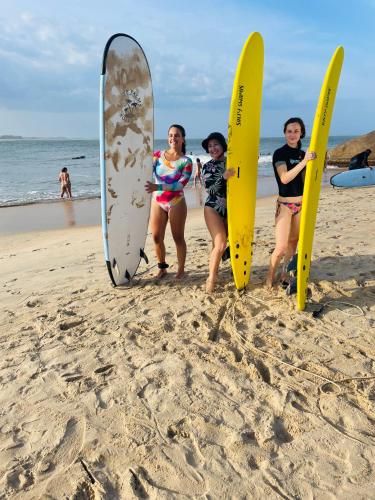 three women are standing on the beach with their surfboards at Eco Aloevera Garden in Pottuvil