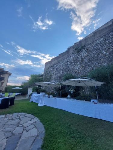 eine Terrasse mit Tischen und Sonnenschirmen auf dem Rasen in der Unterkunft Hotel Bel Sit in Comerio