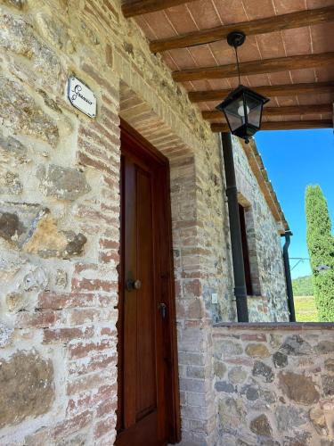 a brick house with a door and a sign on it at Agriturismo La Peschiera in Casole dʼElsa