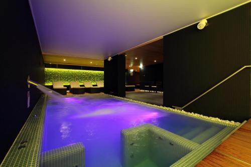 a large jacuzzi tub in a building with purple lighting at Hotel Zena Beauty & Shopping Center in Hévíz