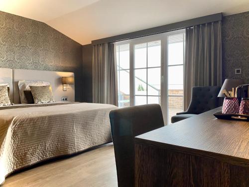 a bedroom with a bed and a desk and a window at Charmehotel Kruishof in Ostend