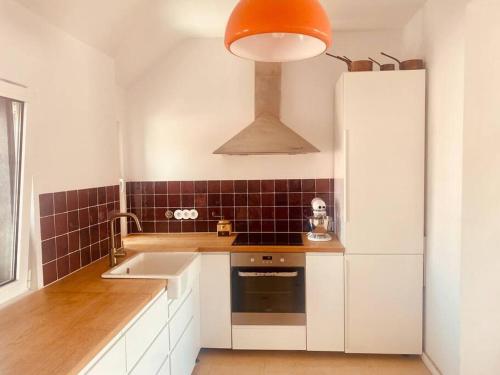 a kitchen with white cabinets and a sink and an orange light at Superb Surf House Next to best Caparica Beach in Costa da Caparica