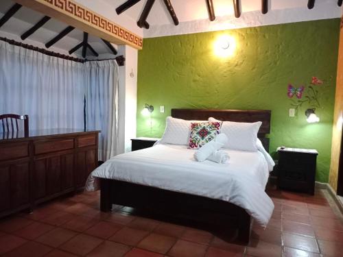 1 dormitorio con 1 cama grande y pared verde en PUEBLITO BOYACENSE Hotel Boutique, en Duitama