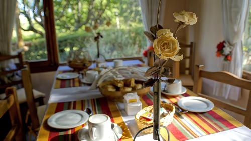 a table with plates and a flower on top of it at Posada La Lucía - Adults Only in Villa General Belgrano