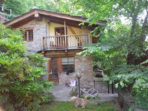 ein Steinhaus mit Balkon und eine Katze im Hof in der Unterkunft L'ontano sulle Alpi in Villar Pellice