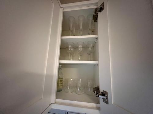 a cupboard filled with glasses sitting inside of a door at Littlehampton House - 4 bedroom house sleeps 8 in Littlehampton