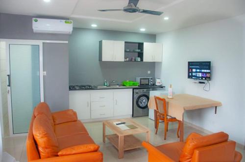 ein Wohnzimmer mit einem Sofa und einem Tisch sowie eine Küche in der Unterkunft Résidences 509 in Lomé