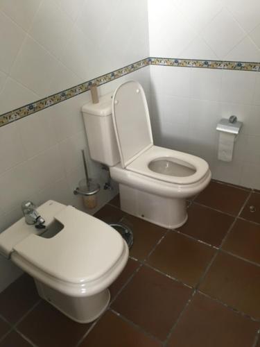 a bathroom with a white toilet and a brown tile floor at Casa Rural "EL CONCEJO" in Aldehuela de la Bóveda