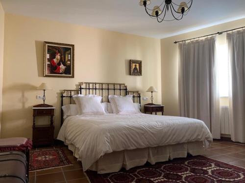 um quarto com uma cama grande com lençóis brancos e almofadas em Casa Rural "EL CONCEJO" em Aldehuela de la Bóveda
