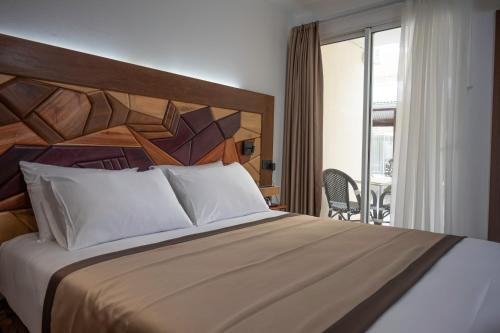 - une chambre avec un grand lit et un balcon dans l'établissement Hôtel Belle Terre Resort, à Macouria