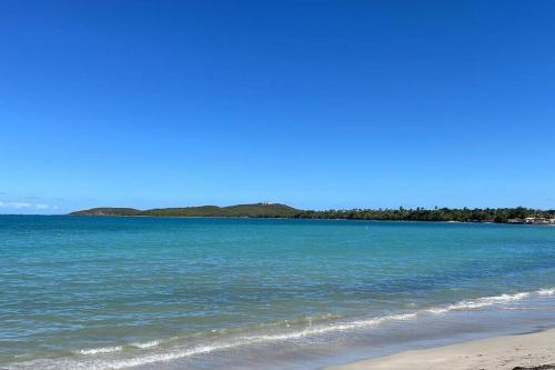 a beach with blue water and trees in the background at Beach Front Apartments Seven Seas in Fajardo