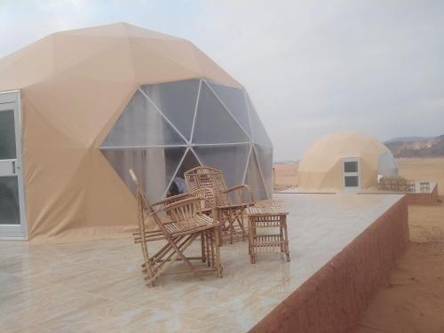 a group of wicker chairs and umbrellas in a desert at Wadi Rum Aviva camp in Wadi Rum