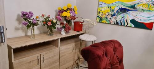 a wooden cabinet with vases of flowers and a painting at Apartament Stephen in Constanţa