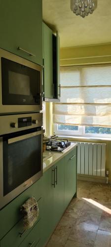 a kitchen with green cabinets and a stove top oven at Apartament Stephen in Constanţa