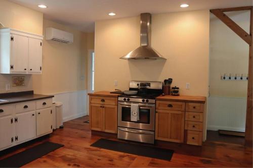 a kitchen with wooden cabinets and a stove top oven at Hillside Haven: Luxe Farm Escape - 5BR-2 King Beds in Swanzey